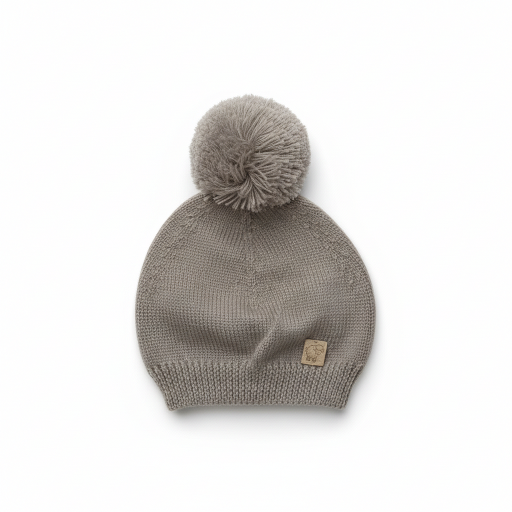 Cappello grigio con pon-pon e patch su sfondo bianco