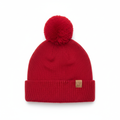 Cappello rosso con pon-pon e patch su sfondo bianco